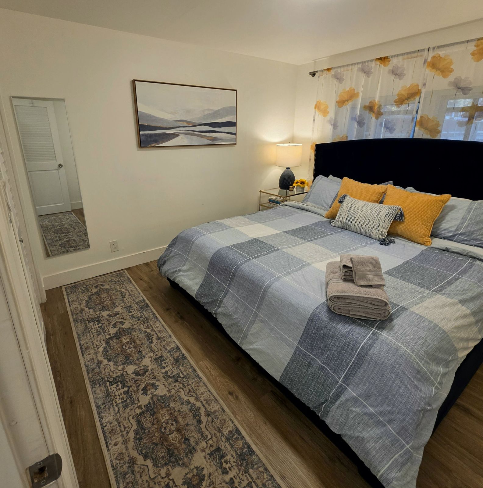 The bedroom from the doorway, with a long patterned runner and a mirror