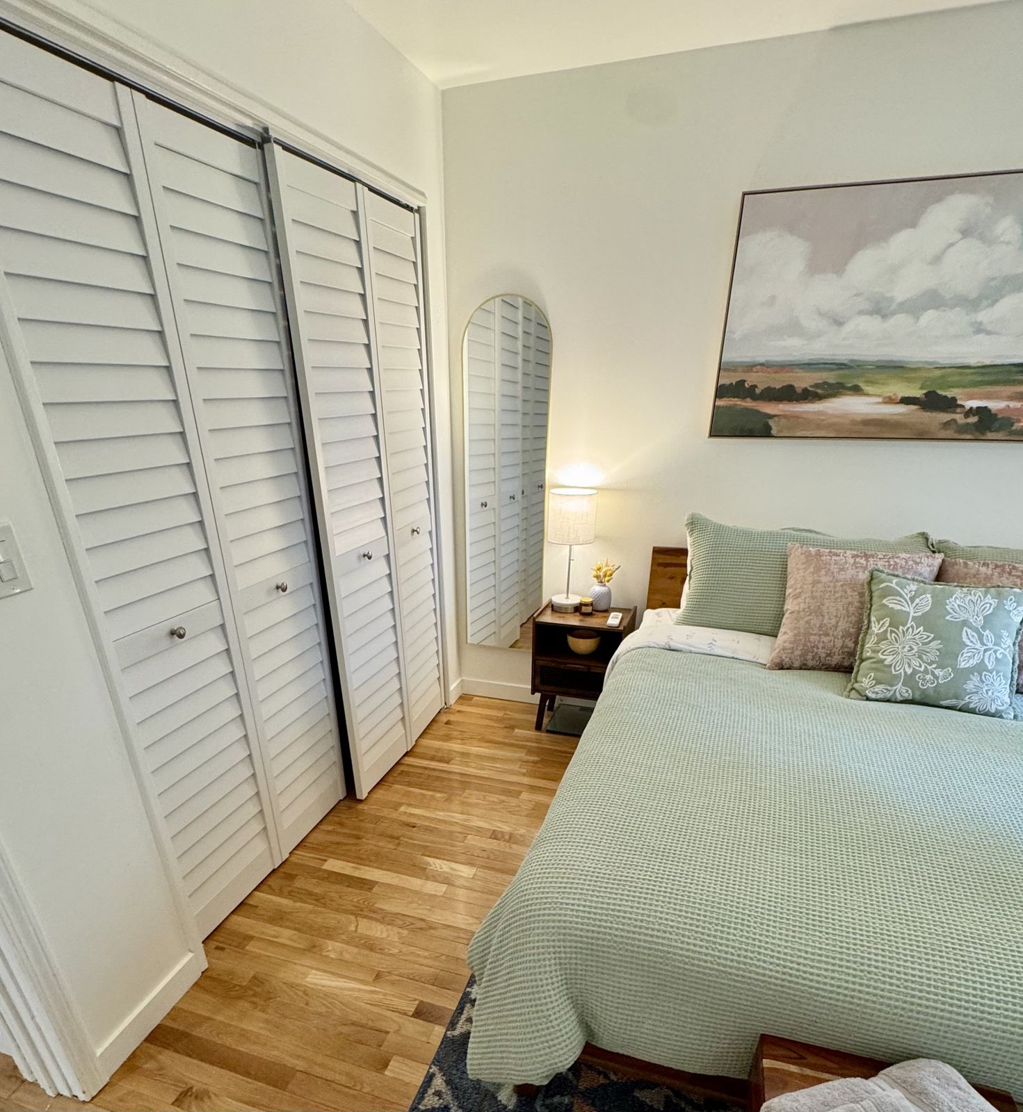 Wall of white louvered closet doors beside the green bed