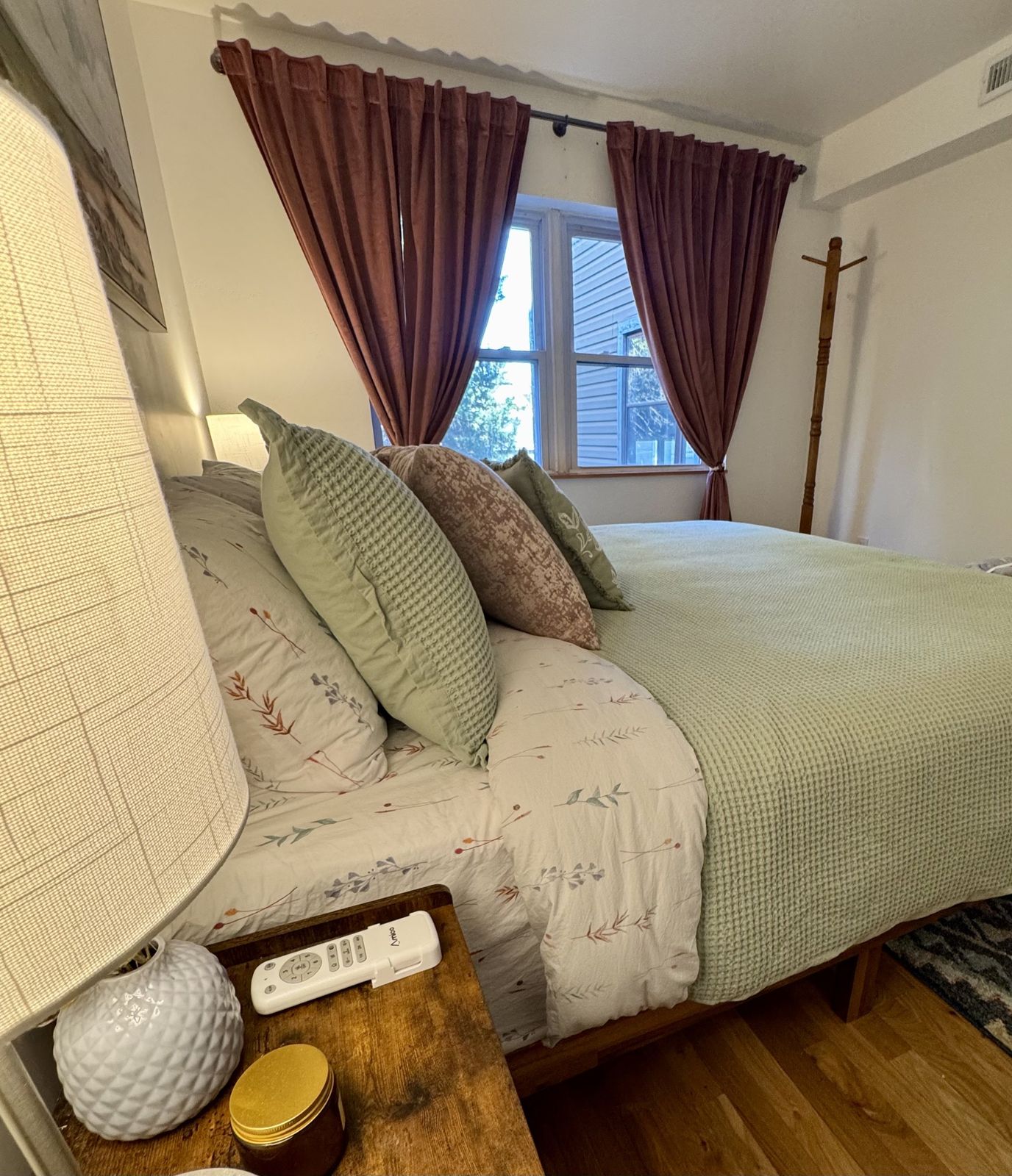 Side view of the green bed with blush velvet curtains at the window