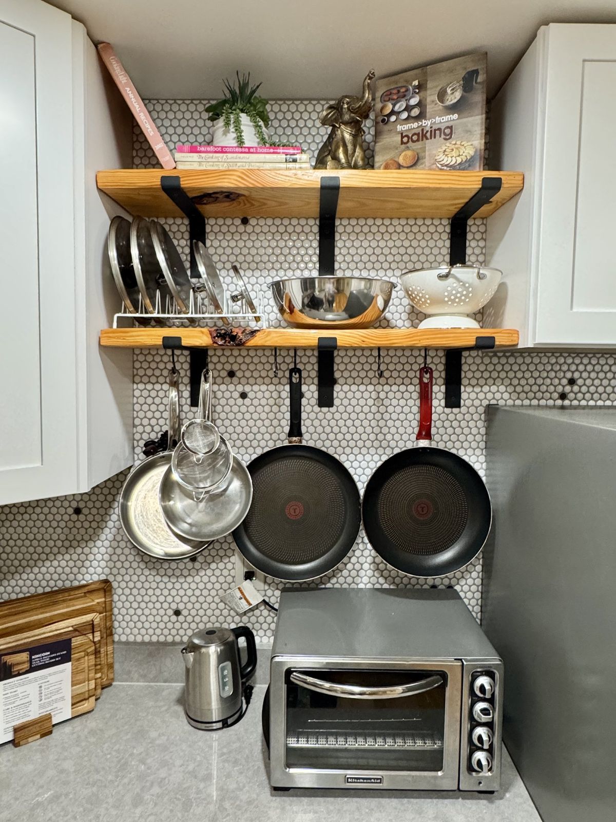 Open wooden shelves with pans hanging below and a toaster oven
