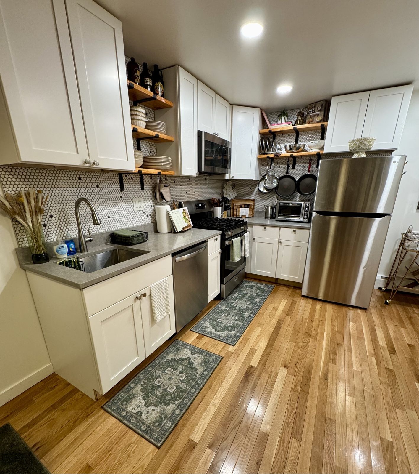 Kitchen with white cabinets, stainless steel appliances and patterned green runners